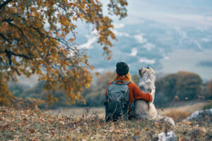 Woman sitting with dog looking at mountain view