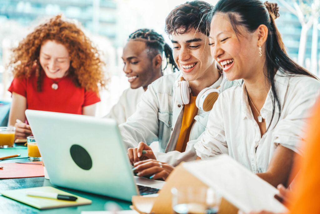 College students laughing with each other while looking at a laptop